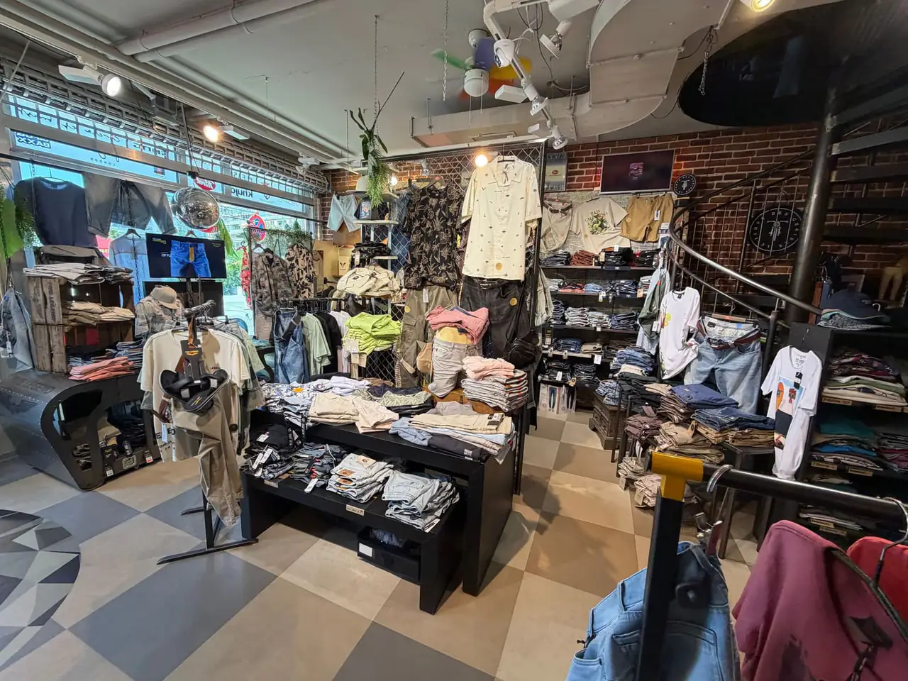 Weitwinkelansicht des Crash Stores mit Jeans, Sportswear und Backsteinwand.