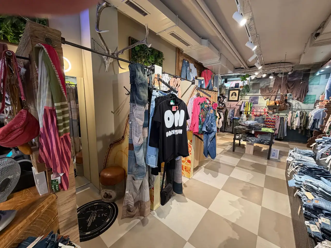 Blick durch den Store mit hängenden Outfits und Denim-Tischen.